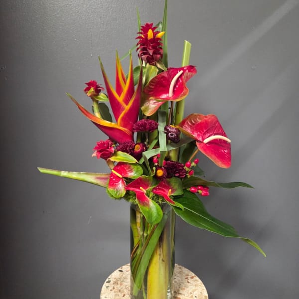 Tropical floral arrangement with red anthuriums in a glass vase