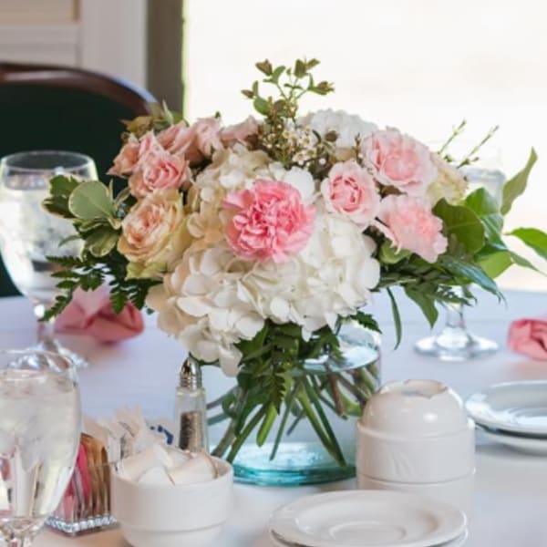 Pink and white floral centerpiece in a glass vase on a table