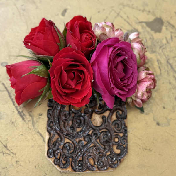 Small bouquet of red and pink roses in a decorative holder