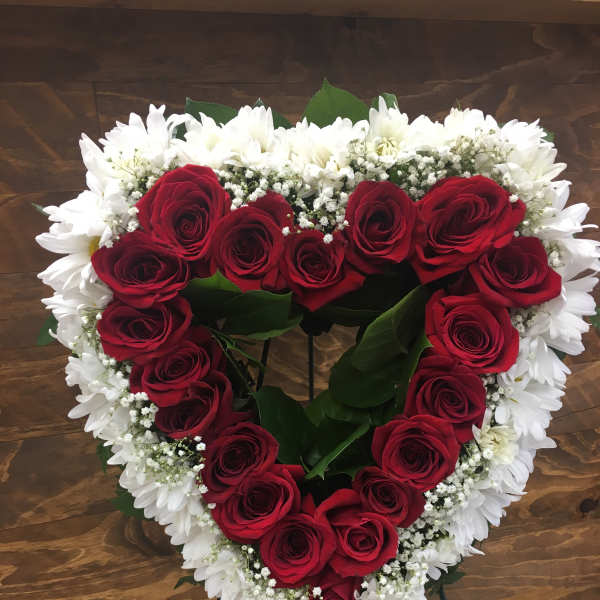 Heart-shaped red rose and white daisy wreath on a stand