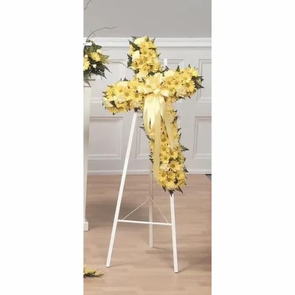Yellow floral cross on a white stand with a ribbon bow