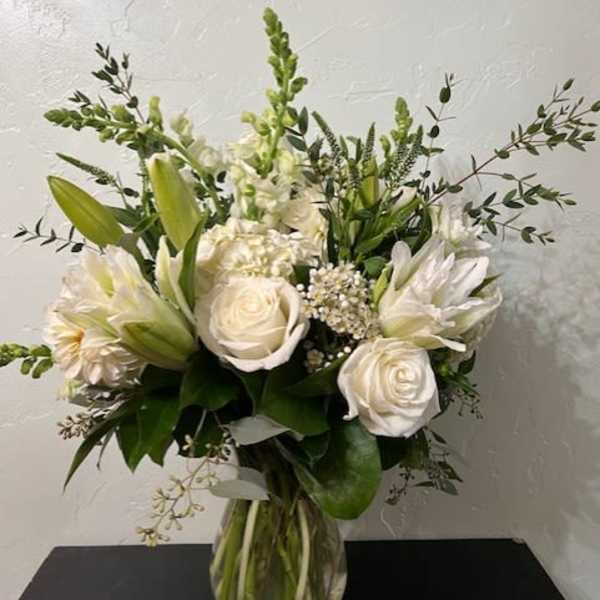 White roses and lilies arranged in a clear glass vase