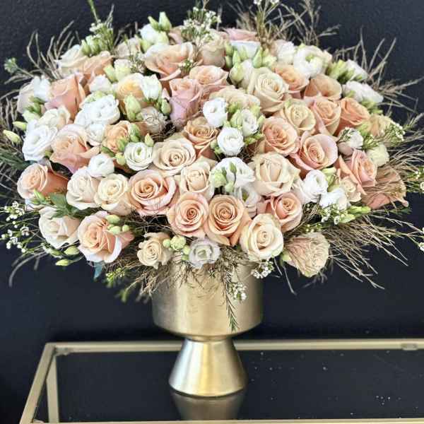Peach and white rose bouquet in a gold pedestal vase