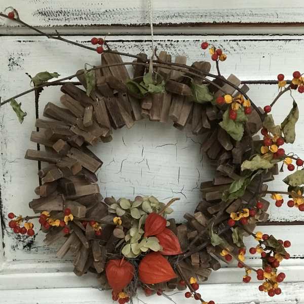 Autumn wreath with red berries and orange pods on a rustic wood ring