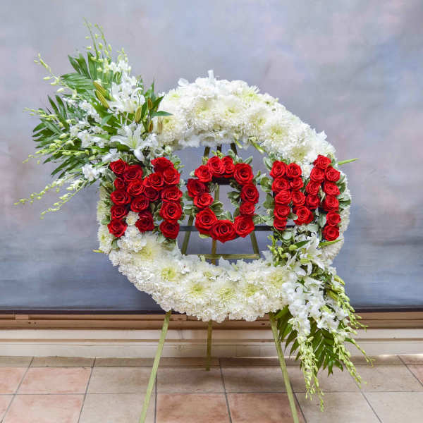 Floral funeral wreath with red roses and white flowers on an easel