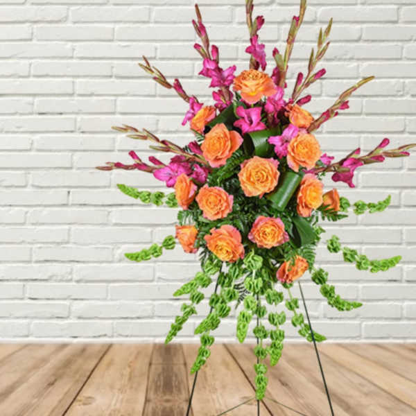 Orange roses and magenta flowers in a tall standing arrangement