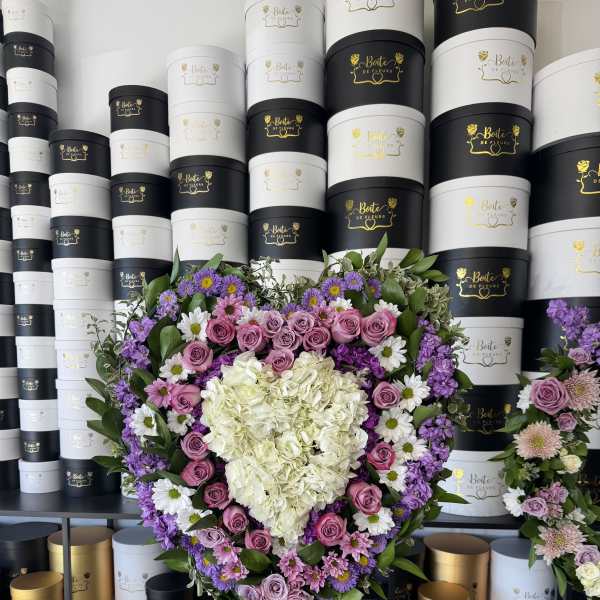 Heart-shaped floral arrangement with pink roses, white hydrangea, and purple flowers