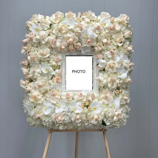Floral photo frame covered in white and blush orchids on an easel