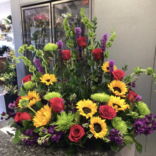 Large arrangement of red roses, sunflowers, and purple flowers
