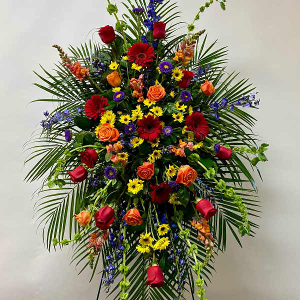 Large standing floral spray with roses, daisies, and palm fronds