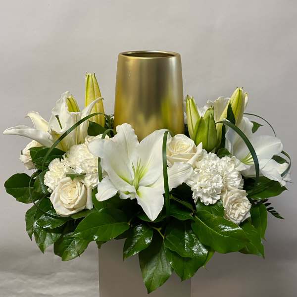 White lilies and roses arranged around a gold vase