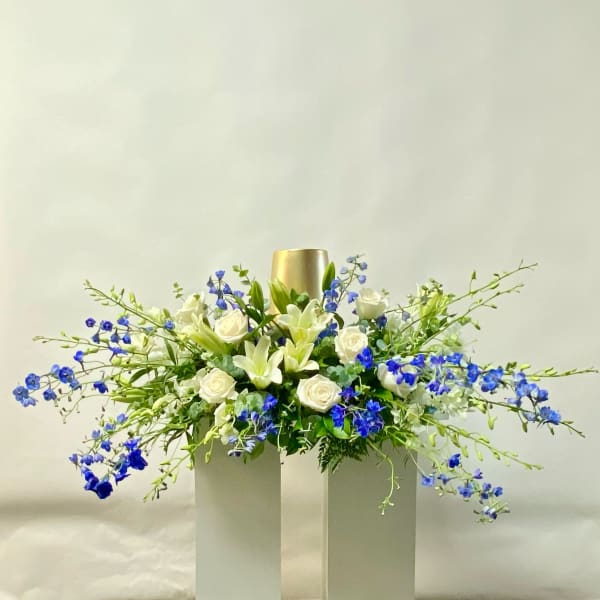 White roses and lilies with blue flowers in a tall gold vase