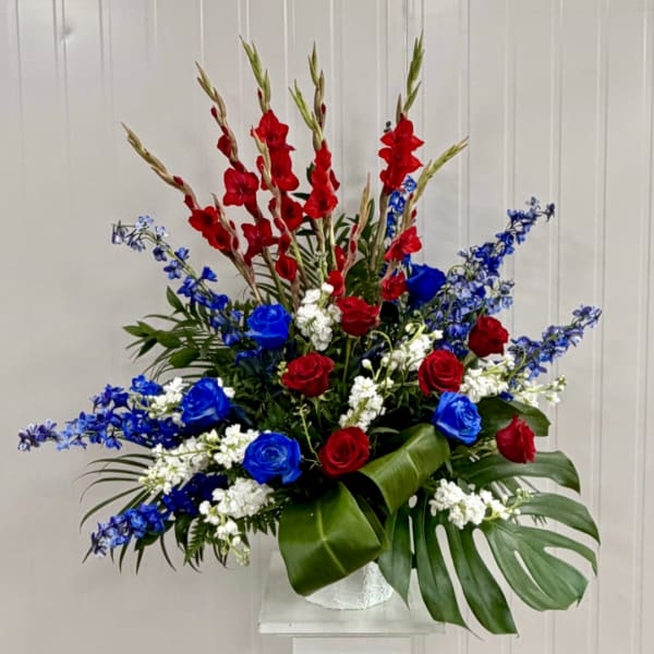 Red and blue roses with white filler flowers in a white vase