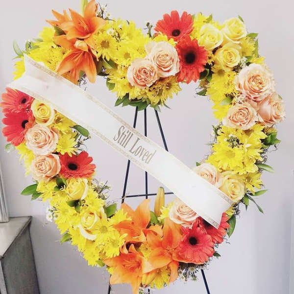 Heart-shaped floral wreath with yellow, orange, red, and peach flowers