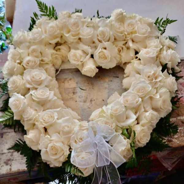 Heart-shaped wreath of white roses with a sheer bow