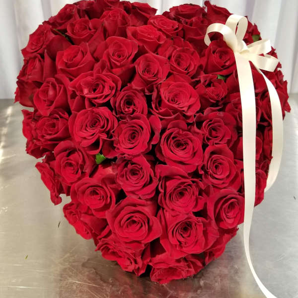 Heart-shaped bouquet of red roses with a white ribbon
