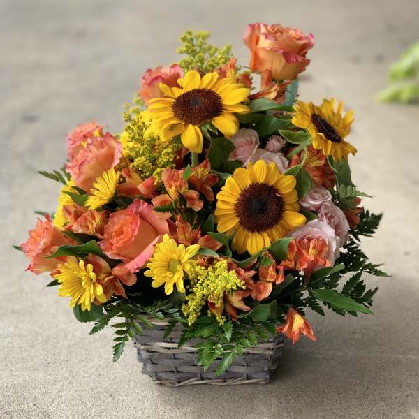 Basket of sunflowers, roses, and orange mixed blooms
