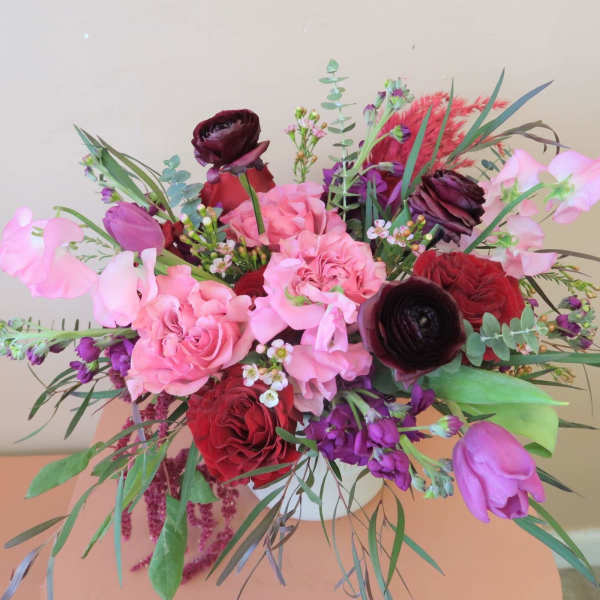 Mixed bouquet of pink, red, and purple flowers with greenery