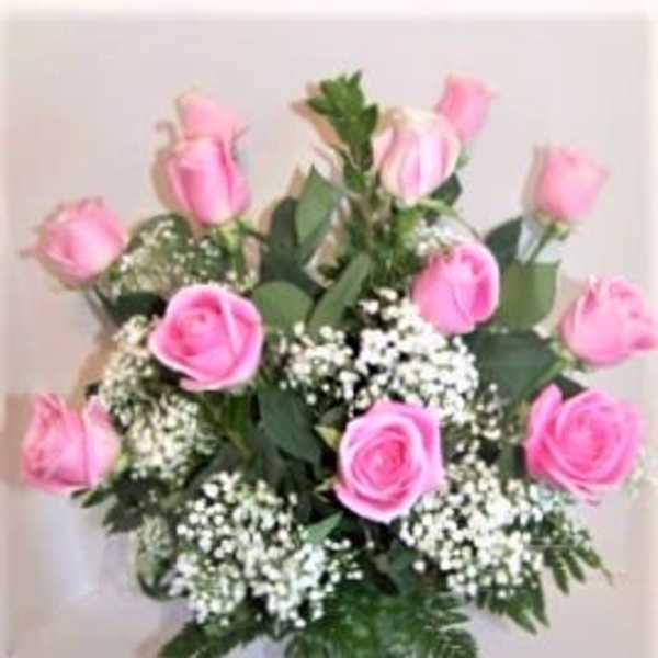 Pink roses arranged in a clear glass vase with white filler flowers