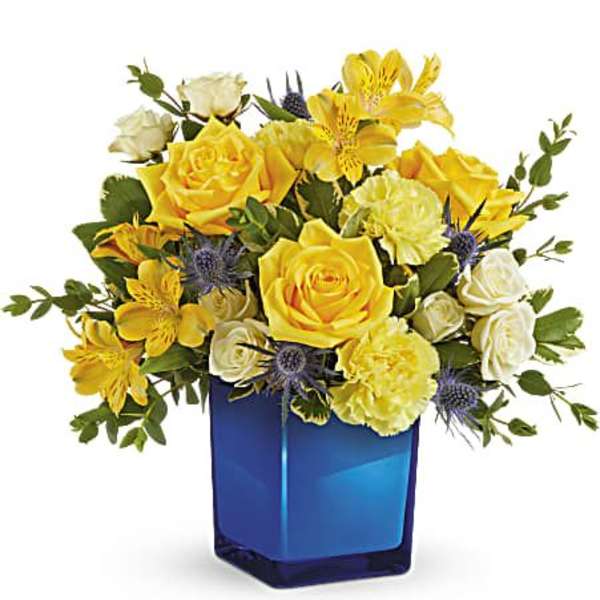 Yellow and white flower arrangement in a blue glass vase