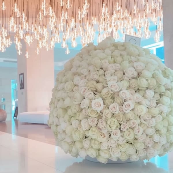 Large spherical arrangement of ivory and blush roses on a low white base in a modern lobby