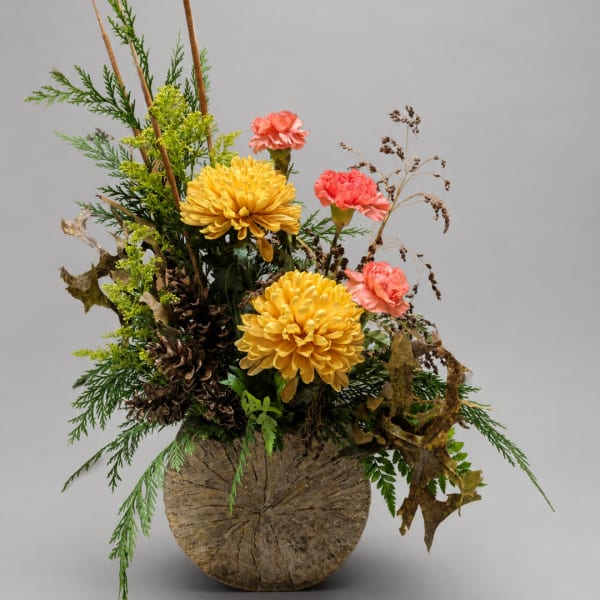 Yellow chrysanthemums and pink carnations in a rustic vase arrangement