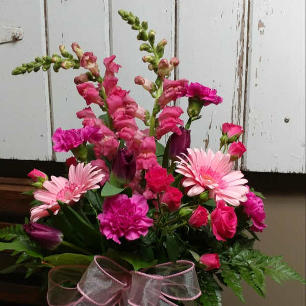 Pink mixed flower bouquet in a glass vase with a sheer ribbon bow
