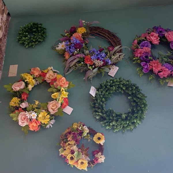 Wall display of colorful floral wreaths and greenery rings