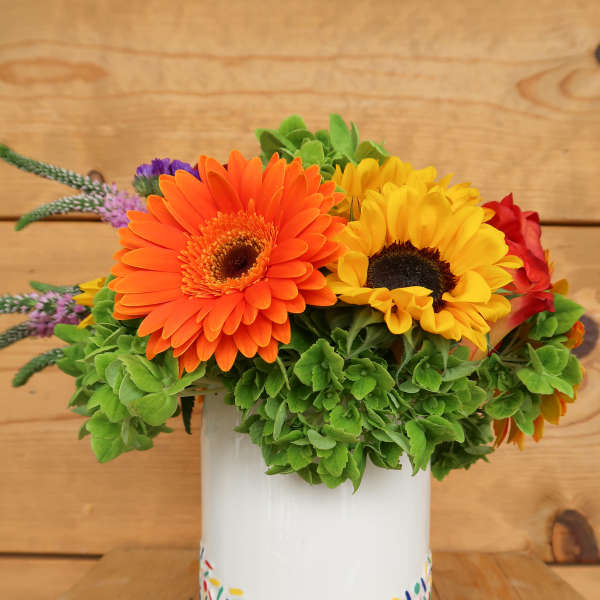 Bright gerbera daisies in a painted white vase