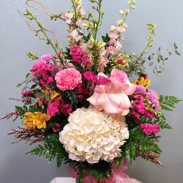 Mixed pink and cream bouquet in a glass vase with a pink ribbon