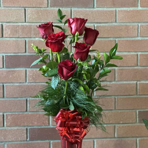 Red roses in a tall red vase with a ribbon bow