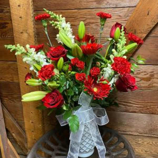 Red and white mixed bouquet with lilies and roses in a white vase