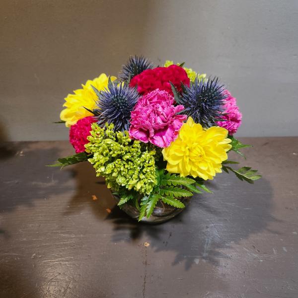 Colorful mixed flower arrangement in a low glass bowl