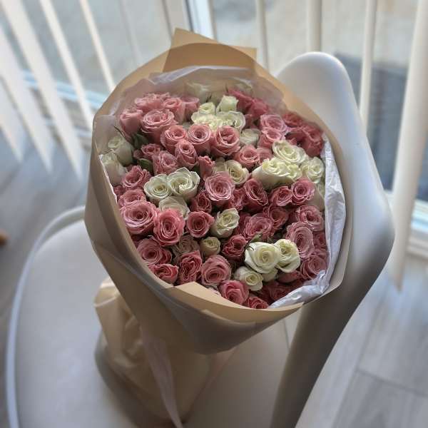 Bouquet of pink and white roses wrapped in tan paper