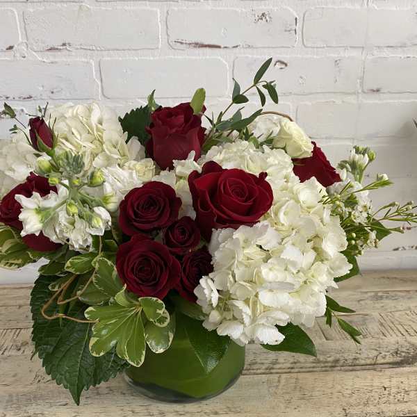 Red roses and white hydrangeas in a green glass vase