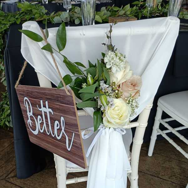 White chair with a floral arrangement and a wooden "Better" sign