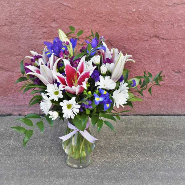 Bouquet of lilies, irises, and white daisies in a glass vase