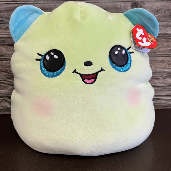 Plush toy with a smiling face and blue ears on a wooden background