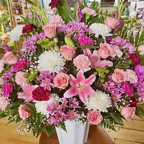 Large pink and white floral arrangement in a white vase