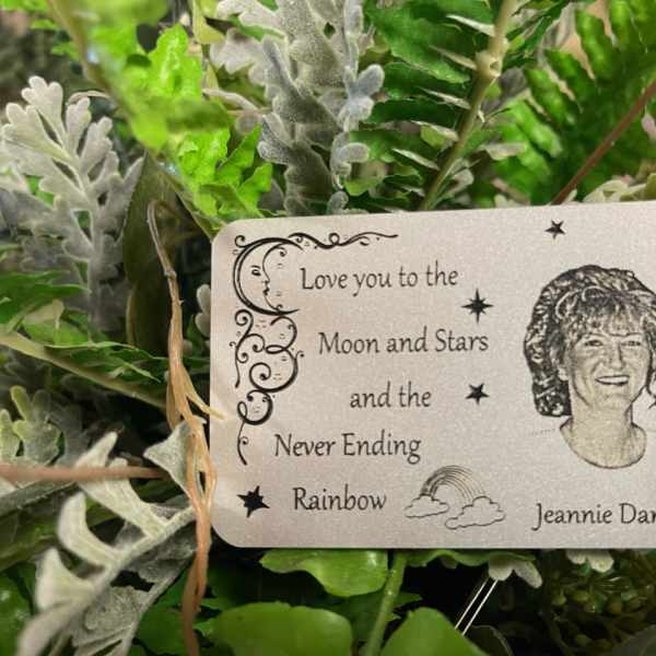 Artificial greenery with a memorial card reading "Love you to the Moon and Stars"