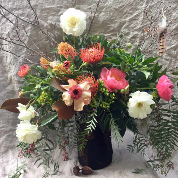 Mixed floral arrangement in a dark vase with white, pink, and orange blooms