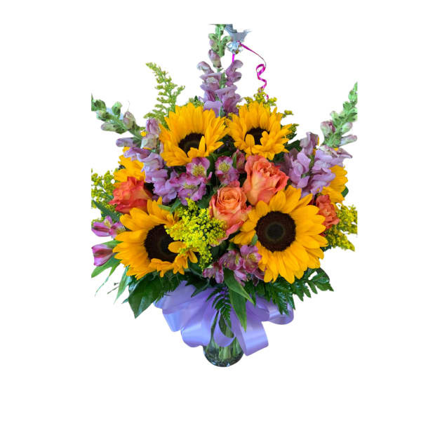 Mixed bouquet of sunflowers, orange roses, and purple flowers in a glass vase with a lavender bow
