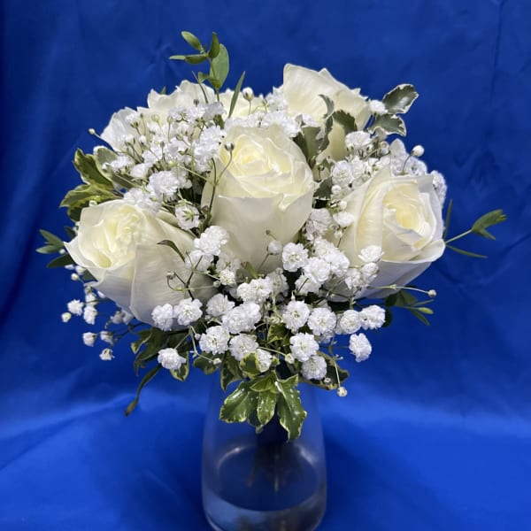 White roses and baby's breath in a clear glass vase