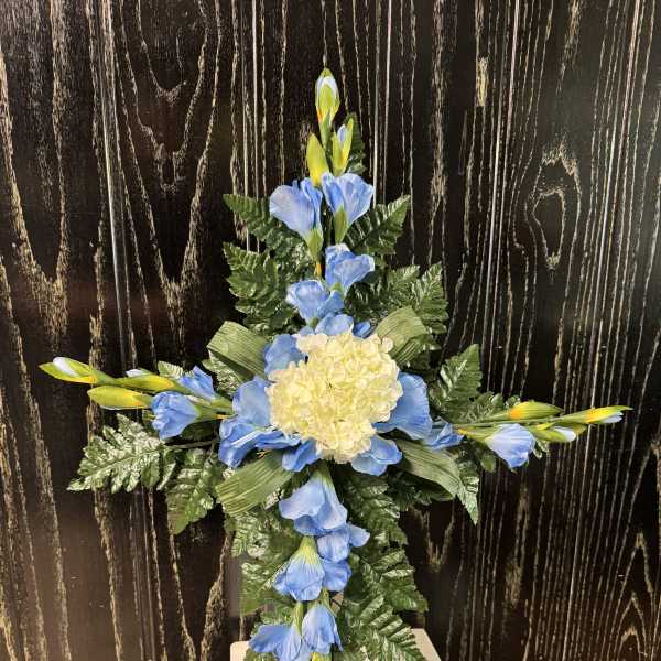 Blue and yellow floral cross arrangement with a pale center