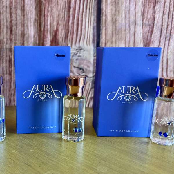 Three blue hair fragrance boxes with matching glass bottles on a wooden surface