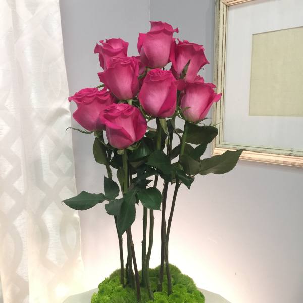 Pink roses arranged in a low glass vase with green moss