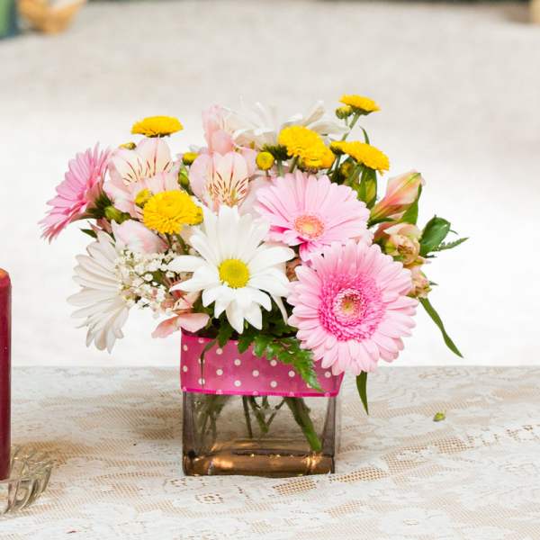 Pink and white mixed bouquet in a square glass vase with a pink ribbon