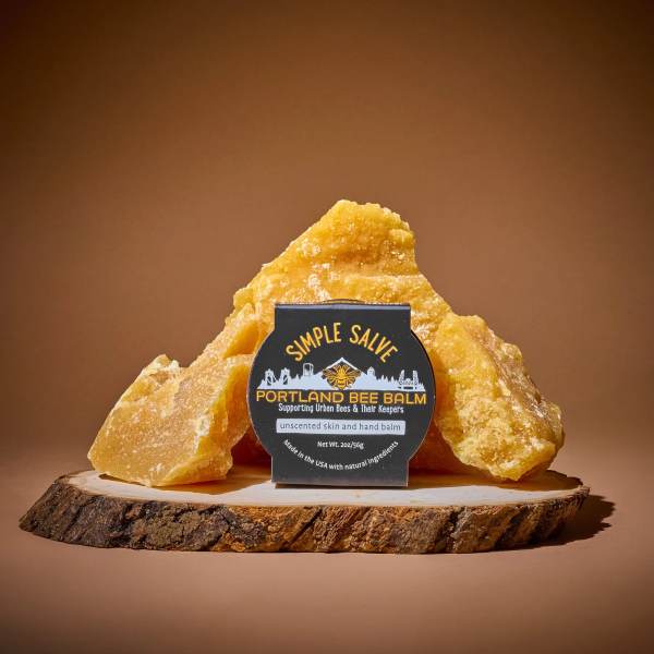 Bee balm package displayed on a wood slice with amber chunks behind it