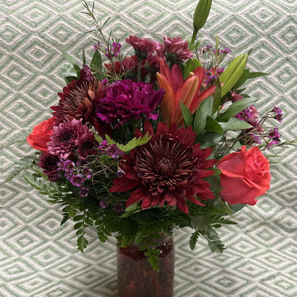 Mixed bouquet of burgundy and pink flowers in a glass vase