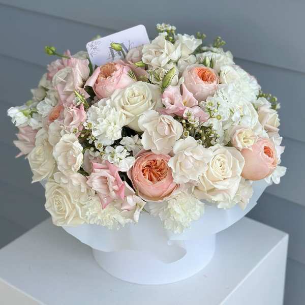 Round bouquet of white and blush roses in white wrapping